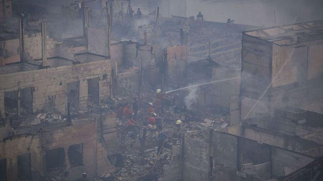 Petugas memadamkan sisa api yang membakar perkampungan padat penduduk di Jalan Lindung Pasar Baru, Teluk Gong, Jakarta Utara, Sabtu (17/7/2021). ANTARA FOTO/Aditya Pradana Putra