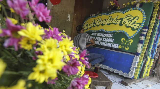 Perajin menyelesaikan produksi karangan bunga duka cita di Kawasan Jalan Raya Pondok Gede, Jakarta Timur, Minggu (18/7/2021). ANTARA FOTO/Asprilla Dwi Adha