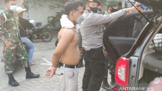 Tersangka penjambretan NS (28) saat dikawal petugas menuju Polres Metro Jakarta Barat usai berupaya menabrak petugas di Pos Penyekatan Kalideres, Jakarta Barat, Minggu (18/7/2021). [ANTARA/HO-Humas Polres Metro Jakarta Barat]. 