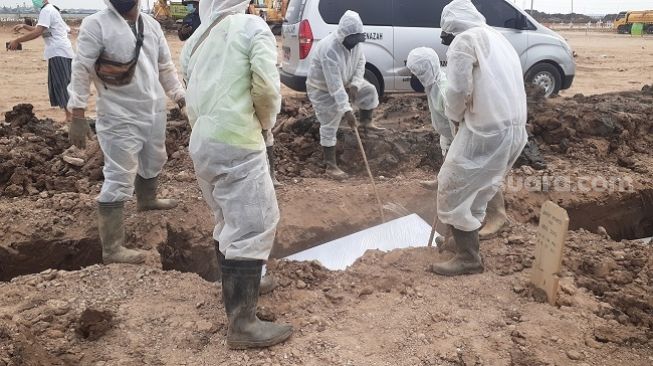 Suasana pilu menyelimuti prosesi pemakaman jenazah Covid-19 di TPU Rorotan, Cilincing, Jakarta Utara, Senin (19/7/2021). (Suara.com/Yaumal Asri)