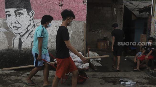 Warga membawa daging kurban yang akan dibagikan secara 'door to door' atau dari rumah ke rumah di kawasan Jati Padang Utara, Pasar Minggu, Jakarta, Selasa (20/7/2021). [Suara.com/Angga Budhiyanto]