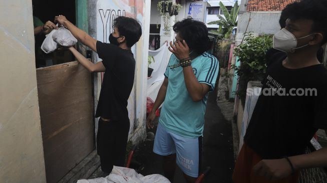 Warga membagikan daging kurban dari rumah ke rumah atau 'door to door' di kawasan Jati Padang Utara, Pasar Minggu, Jakarta, Selasa (20/7/2021). [Suara.com/Angga Budhiyanto]