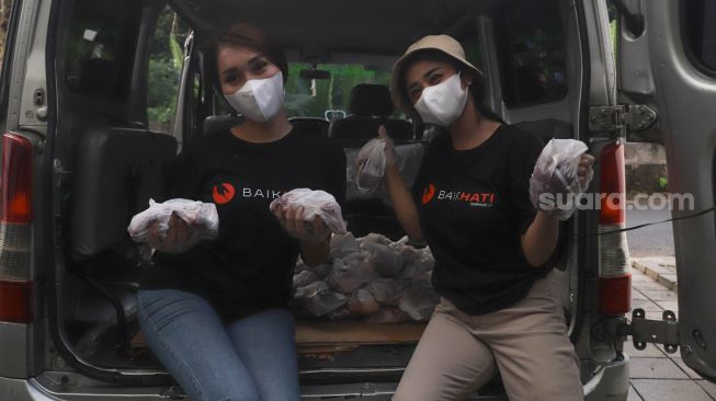 Pedangdut Dewi Perssik dan Lucinta Luna menunjukkan plastik berisi bantuan berupa daging kurban untuk dibagikan kepada warga di sekitar rumahnya di Kawasan Fatmawati, Jakarta Selatan, Selasa (20/7/2021). [Suara.com/Alfian Winanto]