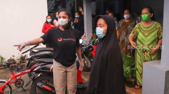 Pedangdut Dewi Perssik membagikan paket bantuan berupa daging kurban dan sembako kepada warga di sekitar rumahnya di Kawasan Fatmawati, Jakarta Selatan, Selasa (20/7/2021). [Suara.com/Alfian Winanto]