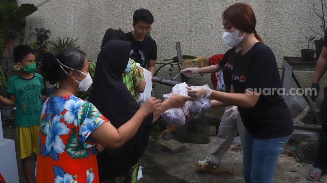 Pedangdut Dewi Perssik dan Lucinta Luna membagikan paket bantuan berupa daging kurban dan sembako kepada warga di sekitar rumahnya di Kawasan Fatmawati, Jakarta Selatan, Selasa (20/7/2021). [Suara.com/Alfian Winanto]