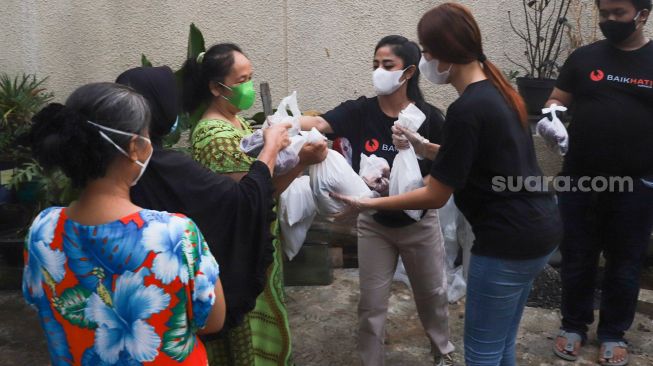 Pedangdut Dewi Perssik dan Lucinta Luna membagikan paket bantuan berupa daging kurban dan sembako kepada warga di sekitar rumahnya di Kawasan Fatmawati, Jakarta Selatan, Selasa (20/7/2021). [Suara.com/Alfian Winanto]