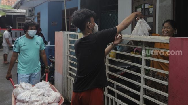 Warga membagikan daging kurban dari rumah ke rumah atau 'door to door' di kawasan Jati Padang Utara, Pasar Minggu, Jakarta, Selasa (20/7/2021). [Suara.com/Angga Budhiyanto]