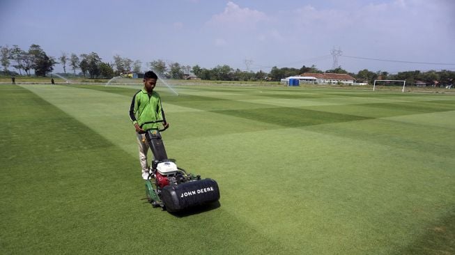 Pekerja memotong rumput lapangan sepak bola menggunakan mesin di Lapangan Desa Purwodadi, Sragi, Kabupaten Pekalongan, Jawa Tengah, Senin (19/7/2021). ANTARA FOTO/Harviyan Perdana Putra