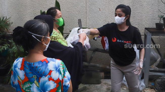 Pedangdut Dewi Perssik membagikan paket bantuan berupa daging kurban dan sembako kepada warga di sekitar rumahnya di Kawasan Fatmawati, Jakarta Selatan, Selasa (20/7/2021). [Suara.com/Alfian Winanto]