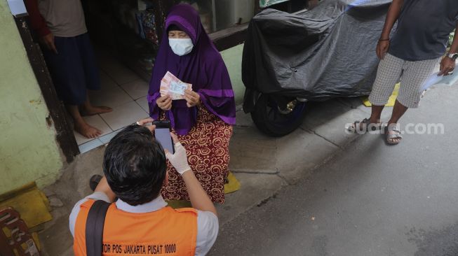 Petugas Pos menyalurkan Bantuan Sosial Tunai (BST) dari rumah ke rumah di kawasan Petojo Selatan, Gambir, Jakarta, Rabu (21/7/2021). [Suara.com/Angga Budhiyanto]