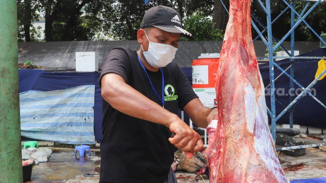 Petugas memotong bagian hewan kurban yang sudah disembelih di Masjid Agung Al Azhar, Jakarta Selatan, Rabu (21/7/2021). [Suara.com/Alfian Winanto]