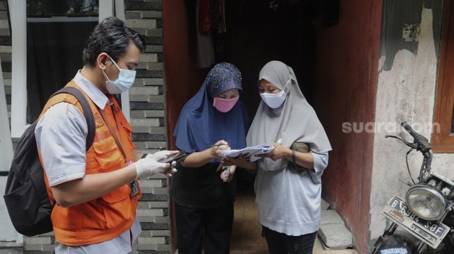 Petugas Pos dibantu petugas RT setempat mendata warga penerima Bantuan Sosial Tunai (BST) di kawasan Petojo Selatan, Gambir, Jakarta, Rabu (21/7/2021). [Suara.com/Angga Budhiyanto]