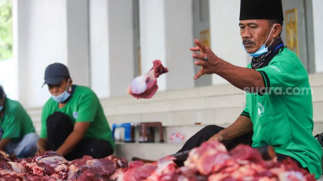 Petugas memotong daging hewan kurban di Masjid Agung Al Azhar, Jakarta Selatan, Rabu (21/7/2021). [Suara.com/Alfian Winanto]