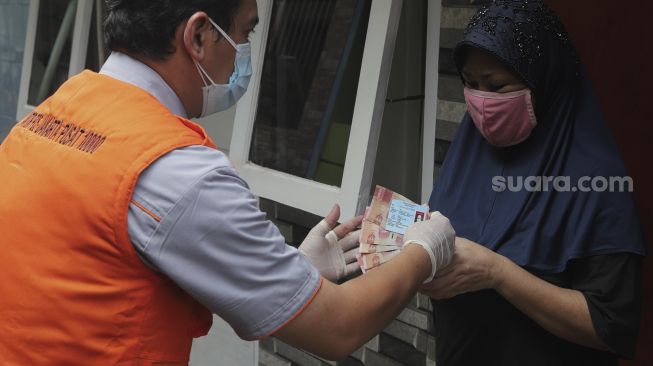 Petugas Pos menyalurkan Bantuan Sosial Tunai (BST) dari rumah ke rumah di kawasan Petojo Selatan, Gambir, Jakarta, Rabu (21/7/2021). [Suara.com/Angga Budhiyanto]