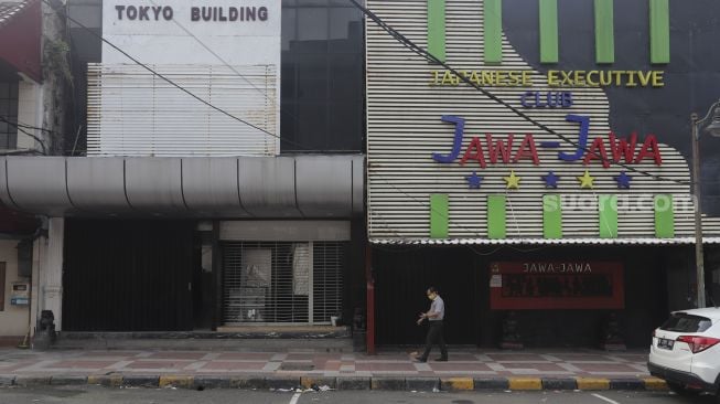 Warga berjalan di depan pertokoan yang tutup di kawasan Melawai, Jakarta, Rabu (21/7/2021). [Suara.com/Angga Budhiyanto]