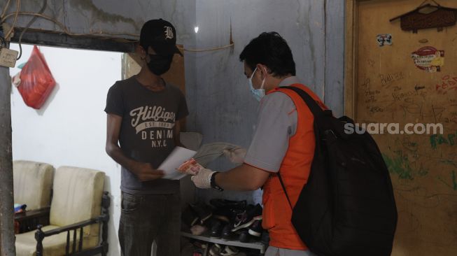 Petugas Pos menyalurkan Bantuan Sosial Tunai (BST) dari rumah ke rumah di kawasan Petojo Selatan, Gambir, Jakarta, Rabu (21/7/2021). [Suara.com/Angga Budhiyanto]