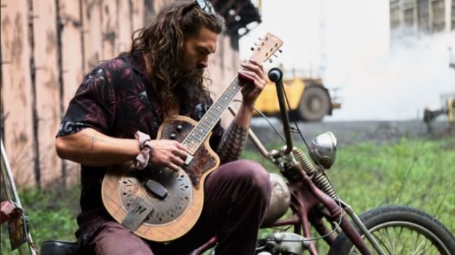 Jason Momoa bermain gitar di atas moge (Harley-Davidson)