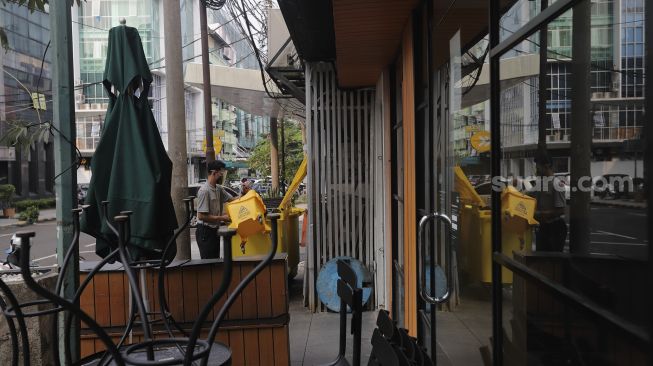 Pekerja beraktivitas di dekat restoran yang tutup di kawasan Melawai, Jakarta, Rabu (21/7/2021). [Suara.com/Angga Budhiyanto]