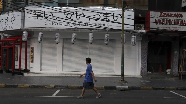 Warga berjalan di depan restoran yang ditutup di kawasan Melawai, Jakarta, Rabu (21/7/2021). [Suara.com/Angga Budhiyanto]