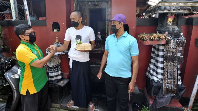 Warga muslim (kiri) memberikan daging kurban kepada warga beragama Hindu pada Hari Raya Idul Adha 1442 H di kawasan Padangsambian, Denpasar, Bali, Selasa (20/7/2021). ANTARA FOTO