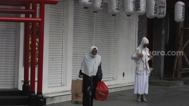 Warga berjalan di depan restoran yang tutup di kawasan Melawai, Jakarta, Rabu (21/7/2021). [Suara.com/Angga Budhiyanto]