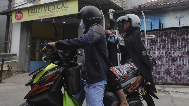 Warga membawa tabung oksigen medis usai diisi ulang di toko alat kesehatan Fauzi Medical, Matraman, Jakarta, Kamis (22/7/2021). [Suara.com/Angga Budhiyanto]