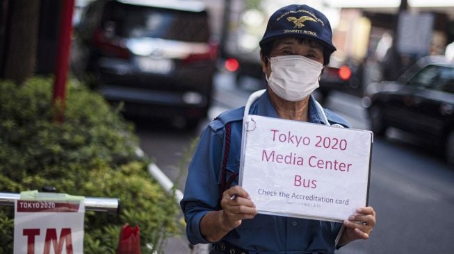 Petugas menunggu tibanya bus yang akan membawa peserta Olimpiade Tokyo 2020 di Shinjuku, Tokyo, Jepang, Rabu (21/7/2021).  ANTARA FOTO/Sigid Kurniawan