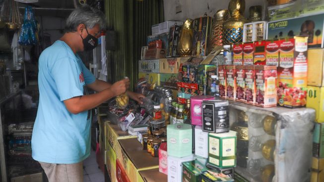 Penjual membersihkan barang oleh-oleh khas haji di sekitar kawasan Asrama Haji, Pondok Gede, Jakarta Timur, Kamis (22/7/2021). [Suara.com/Alfian Winanto]