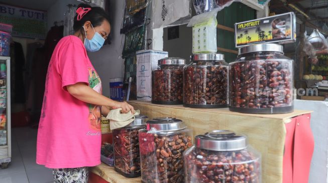 Penjual membersihkan barang oleh-oleh khas haji di sekitar kawasan Asrama Haji, Pondok Gede, Jakarta Timur, Kamis (22/7/2021). [Suara.com/Alfian Winanto]