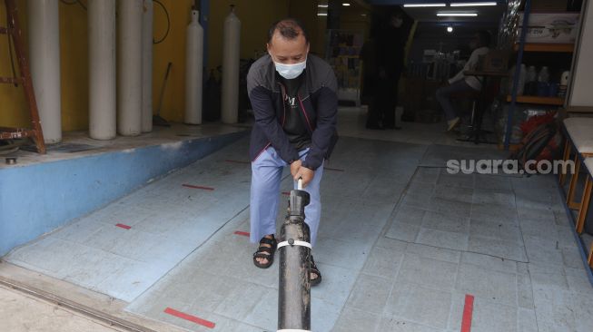 Warga membawa tabung oksigen medis usai diisi ulang di toko alat kesehatan Fauzi Medical, Matraman, Jakarta, Kamis (22/7/2021). [Suara.com/Angga Budhiyanto]