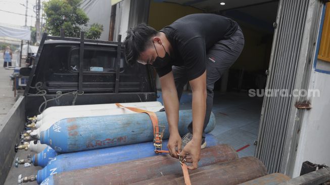 Warga memindahkan tabung oksigen medis untuk diisi ulang di toko alat kesehatan Fauzi Medical, Matraman, Jakarta, Kamis (22/7/2021). [Suara.com/Angga Budhiyanto]