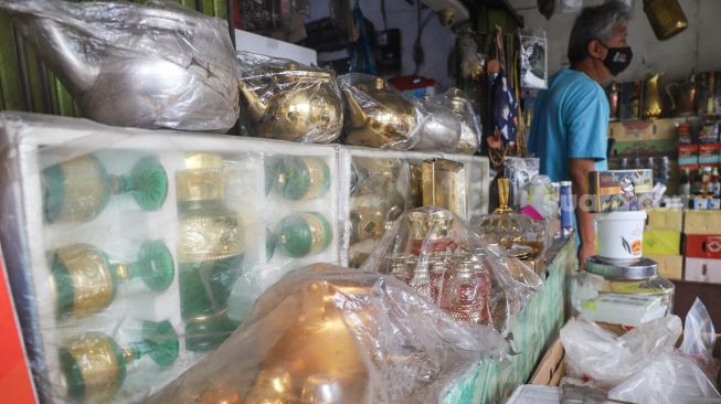 Penjual membersihkan barang oleh-oleh khas haji di sekitar kawasan Asrama Haji, Pondok Gede, Jakarta Timur, Kamis (22/7/2021). [Suara.com/Alfian Winanto]