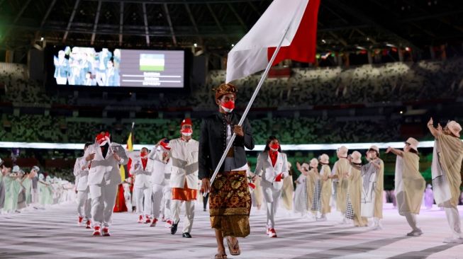 Peselancar putra Indonesia, Rio Waida saat membawa bendera Merah Putih dalam parade kontingen negara-negara peserta Olimpiade Tokyo 2020 di Stadion Nasional Jepang, Jumat (23/7/2021) malam WIB. Odd ANDERSEN / AFP.