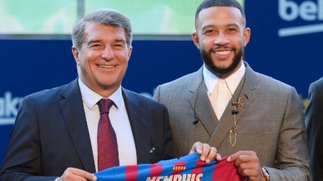 Pemain baru Barcelona Memphis Depay (kanan) bersama presiden klub Joan Laporta saat diperkenalkan secara resmi oleh klub di stadion Camp Nou di Barcelona pada 22 Juli 2021. LLUIS GENE / AFP