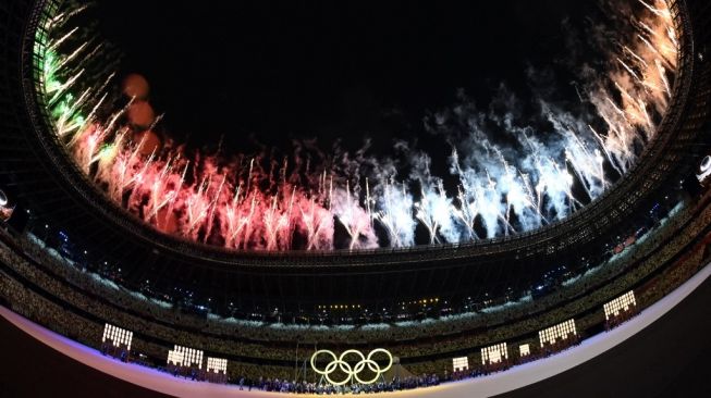 Kembang api menyala di langit Stadion Nasional Jepang yang merupakan venue upacara pembukaan Olimpiade Tokyo 2020, Jumat (23/7/2021) malam WIB. AFP.