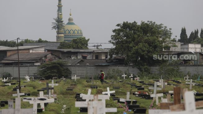 Warga berjalan usai melayat ke makam keluarganya yang meninggal dunia karena COVID-19 di TPU Tegal Alur, Jakarta, Jumat (23/7/2021). [Suara.com/Angga Budhiyanto]