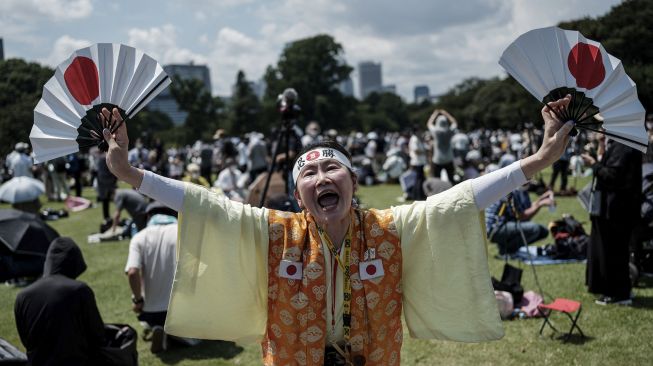 Penggemar berat Olimpiade Kyoko Ishikawa yang telah menghadiri setiap Olimpiade Musim Panas dalam 30 tahun terakhir, mengungkapkan rasa terima kasihnya saat Blue Impulse, tim aerobatik Angkatan Udara Bela Diri Jepang (JASDF), melakukan pertunjukan membentuk cincin Olimpiade di langit Tokyo, pada (23/7/2021). [Yasuyoshi CHIBA / AFP]