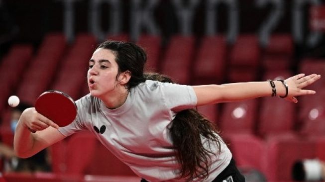 Petenis meja Suriah Hend Zaza bersiap serve saat melawan atlet Austria Liu Jia dalam babak penyisihan tunggal putri tenis meja di Tokyo Metropolitan Gymnasium dalam Olimpiade Tokyo 2020 di Tokyo pada 24 Juli 2021. (AFP/ANNE-CHRISTINE POUJOULAT) 