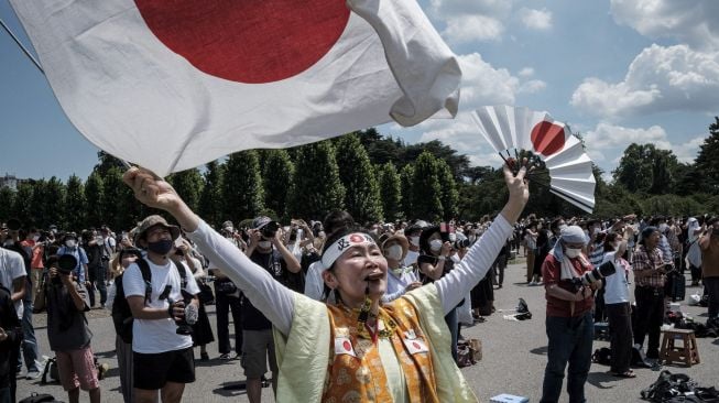 Penggemar berat Olimpiade Kyoko Ishikawa yang telah menghadiri setiap Olimpiade Musim Panas dalam 30 tahun terakhir, mengungkapkan rasa terima kasihnya saat Blue Impulse, tim aerobatik Angkatan Udara Bela Diri Jepang (JASDF), melakukan pertunjukan membentuk cincin Olimpiade di langit Tokyo, pada (23/7/2021). [Yasuyoshi CHIBA / AFP]