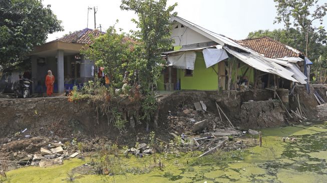 Warga melihat kondisi rumah yang rusak akibat longsor di Desa Kertasmaya, Indramayu, Jawa Barat, Sabtu (24/7/2021). [ANTARA FOTO/Dedhez Anggara]