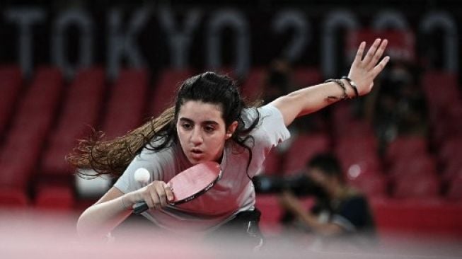 Petenis meja Suriah Hend Zaza bersiap serve saat melawan atlet Austria Liu Jia dalam babak penyisihan tunggal putri tenis meja di Tokyo Metropolitan Gymnasium dalam Olimpiade Tokyo 2020 di Tokyo pada 24 Juli 2021. (AFP/ANNE-CHRISTINE POUJOULAT) 