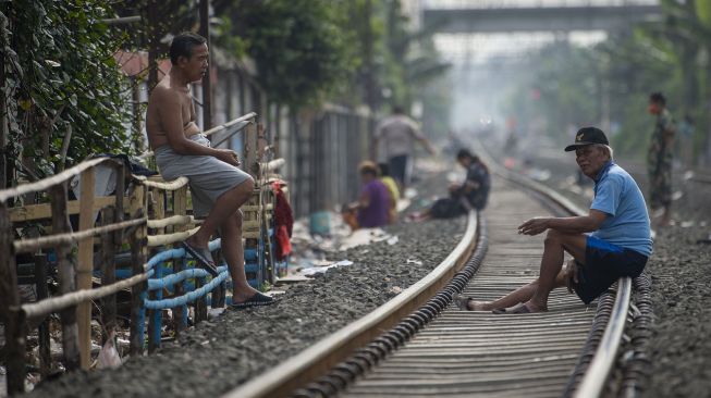 Warga berjemur di jalur kereta api kawasan Tanjung Priok, Jakarta, Sabtu (24/7/2021).  ANTARA FOTO/Aditya Pradana Putra
