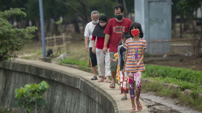 Warga berjalan sambil berjemur di tepi Danau Cincin, Tanjung Priok, Jakarta, Sabtu (24/7/2021). ANTARA FOTO/Aditya Pradana Putra