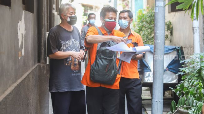 Petugas Pos Indonesia saat mendistribusikan Bantuan Sosial Tunai (BST) secara Door to Door kepada warga di kawasan Glodok, Jakarta Barat, Minggu (25/7/2021). [Suara.com/Alfian Winanto]