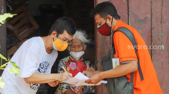 Petugas Pos Indonesia mendistribusikan Bantuan Sosial Tunai (BST) secara Door to Door kepada warga di kawasan Glodok, Jakarta Barat, Minggu (25/7/2021). [Suara.com/Alfian Winanto]