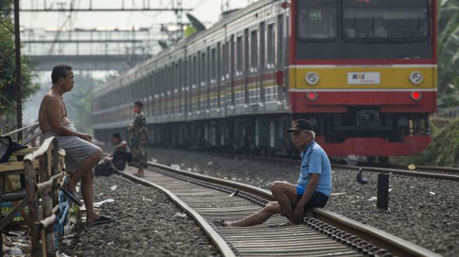 Warga berjemur di jalur kereta api kawasan Tanjung Priok, Jakarta, Sabtu (24/7/2021).  ANTARA FOTO/Aditya Pradana Putra
