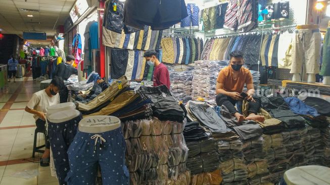 Pedagang menunggu pembeli di Blok B Pasar Tanah Abang, Jakarta Pusat, Senin (26/7/2021). [Suara.com/Alfian Winanto]