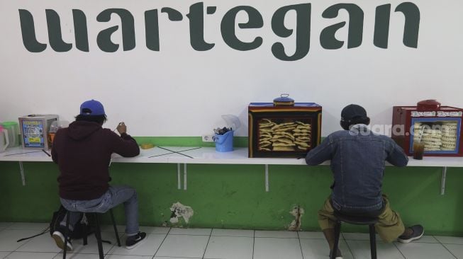 Pembeli menyantap hidangan makanan di Wartegan, Ampera, Jakarta, Senin (26/7/2021). [Suara.com/Angga Budhiyanto]