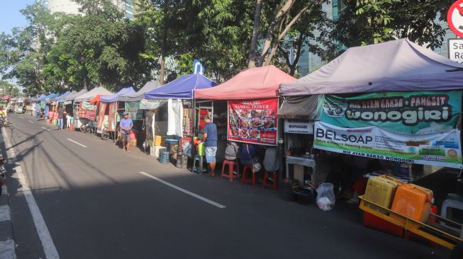 Pedagang kaki lima menjajakan daganganya di sekitar kawasan Sudirman, Jakarta Pusat, Senin (26/7/2021). [Suara.com/Alfian Winanto]