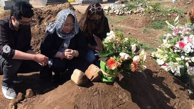 Dewi Irawan bersama dua anaknya di makam sang suami. [Instagram]